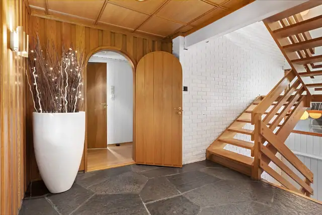 Entré med skiferstein på gulv, gulvvarme, malt overflate og panel på vegger. Trevirke i tak med downlights.