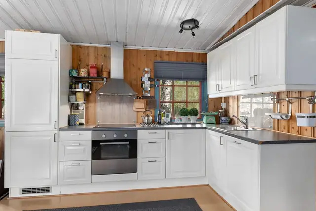 Monterte glassplater over vask og komfyr hindrer fukt og slitasje på panelet.
