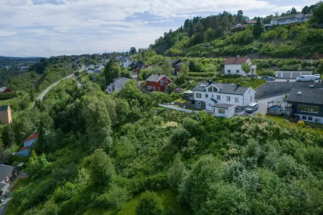 Tomten ligger på nedsiden av det hvite huset.