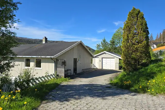 Innholdsrik enebolig med steinlagt gårdsplass og garasje.