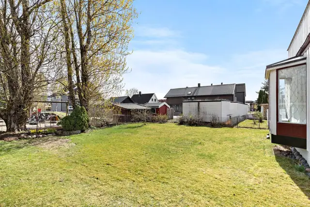 Flat tomt og stor hage med gode solforhold - Selger opplyser at trær mot friareal skal felles av kommunen.
