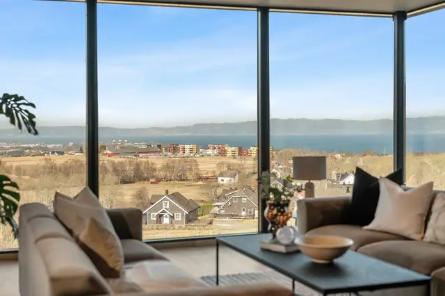 Arkitektur og utsikt i perfekt samspill. Fra sofakroken ser du Trondheimsfjorden, Lade og åpent kulturlandskap - en levende ramme som skifter med årstidene og lysforholdene.