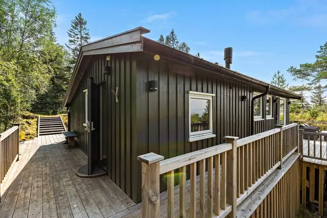 Et hyggelig inngangsparti med utebelysning og terrasse som omkranser hytta.