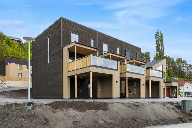 Fasade av boligen. Det gjøres oppmerksom på at uteområde er redigert med AI. det er noen avvik i terrenget på siden av boligen.