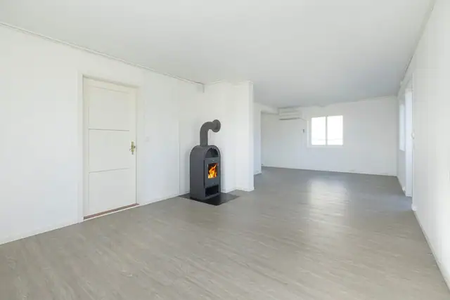 Romslig stue med vedovn som skaper en lun og hyggelig atmosfære.