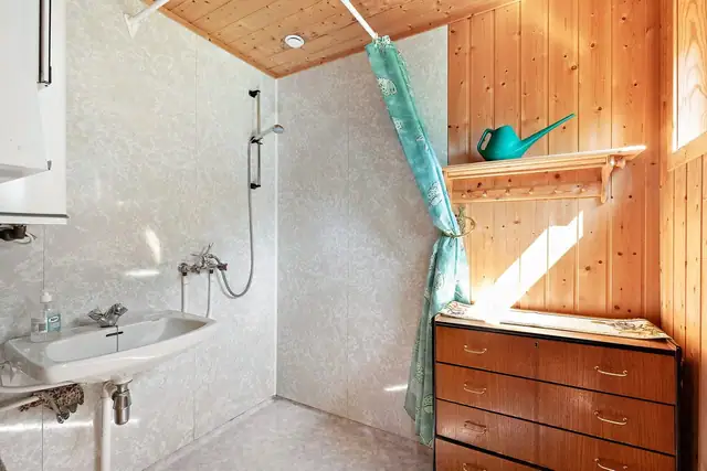 Badet inneholder dusjsone med dusjgarnityr på vegg og servant.