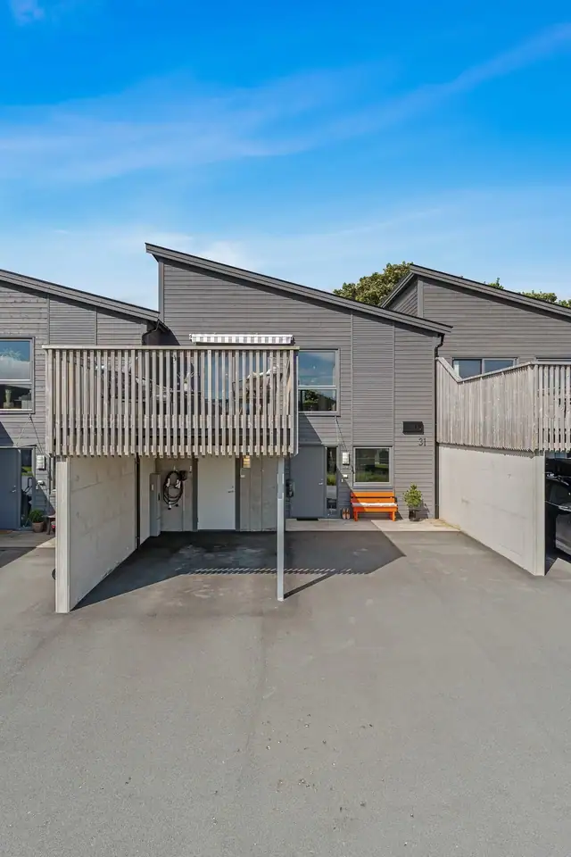 Fasade. Parkering i carport. Asfaltert gårdsplass.