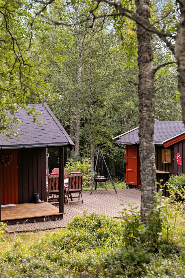 Hyggelig tun med platting mellom hytta og uthuset.