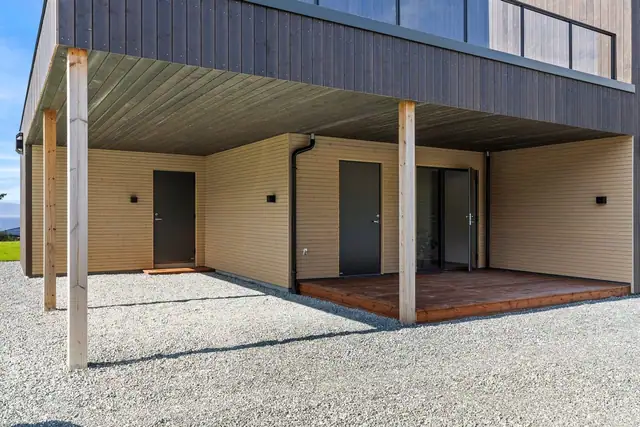 Det overbygde inngangspartiet gir en praktisk adkomst til boligen, med enkel tilgang til både vaskerom og bod, samt videre til parkering i carport.