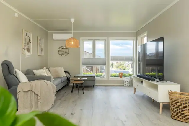 Romslig stue med store vinduer som slipper inn rikelig med naturlig lys. Nyere varmepumpe.