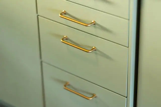 Detaljbilde fra kjøkken, håndtak i messingfarge.